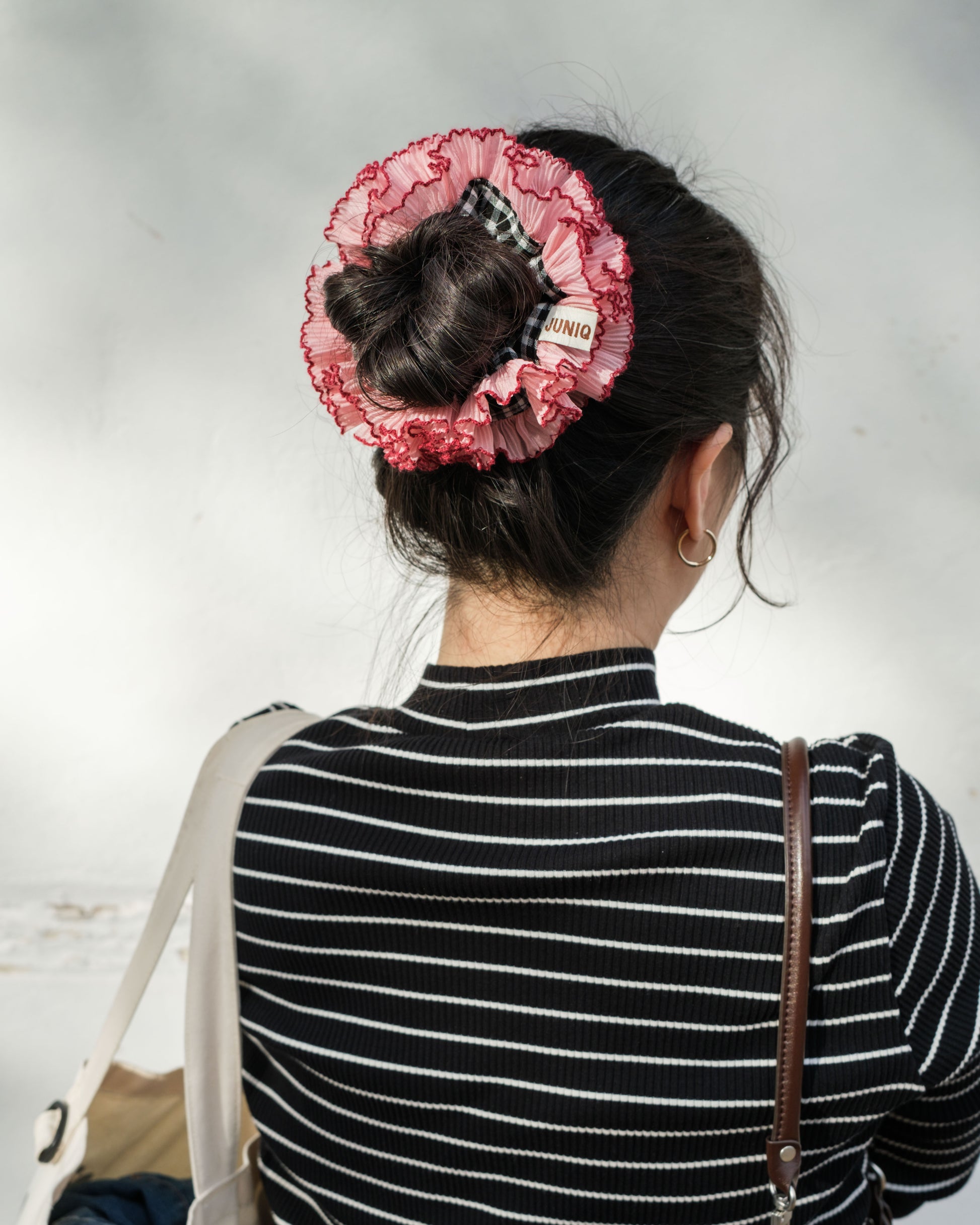 model wearing juniq brand scrunchie, double frilled, black gingham, pink ruffle trim, in her bun