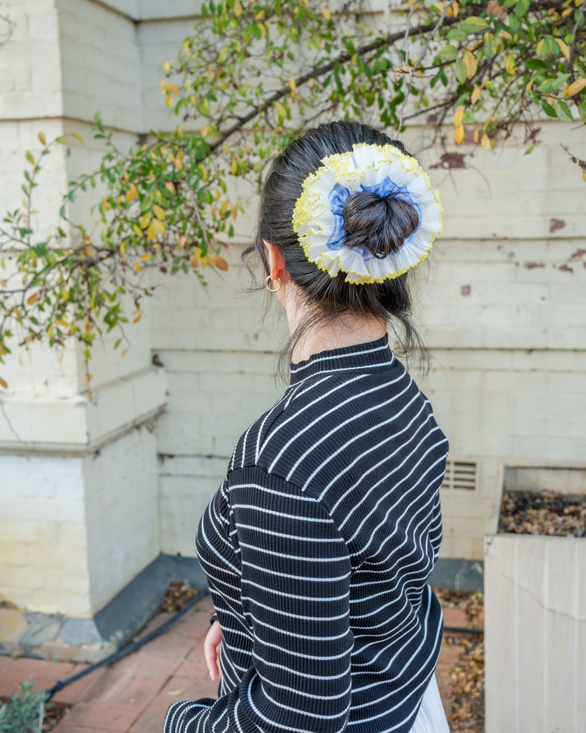 model wearing juniq brand scrunchie, double frilled, light blue gingham, white ruffle trim, in her bun