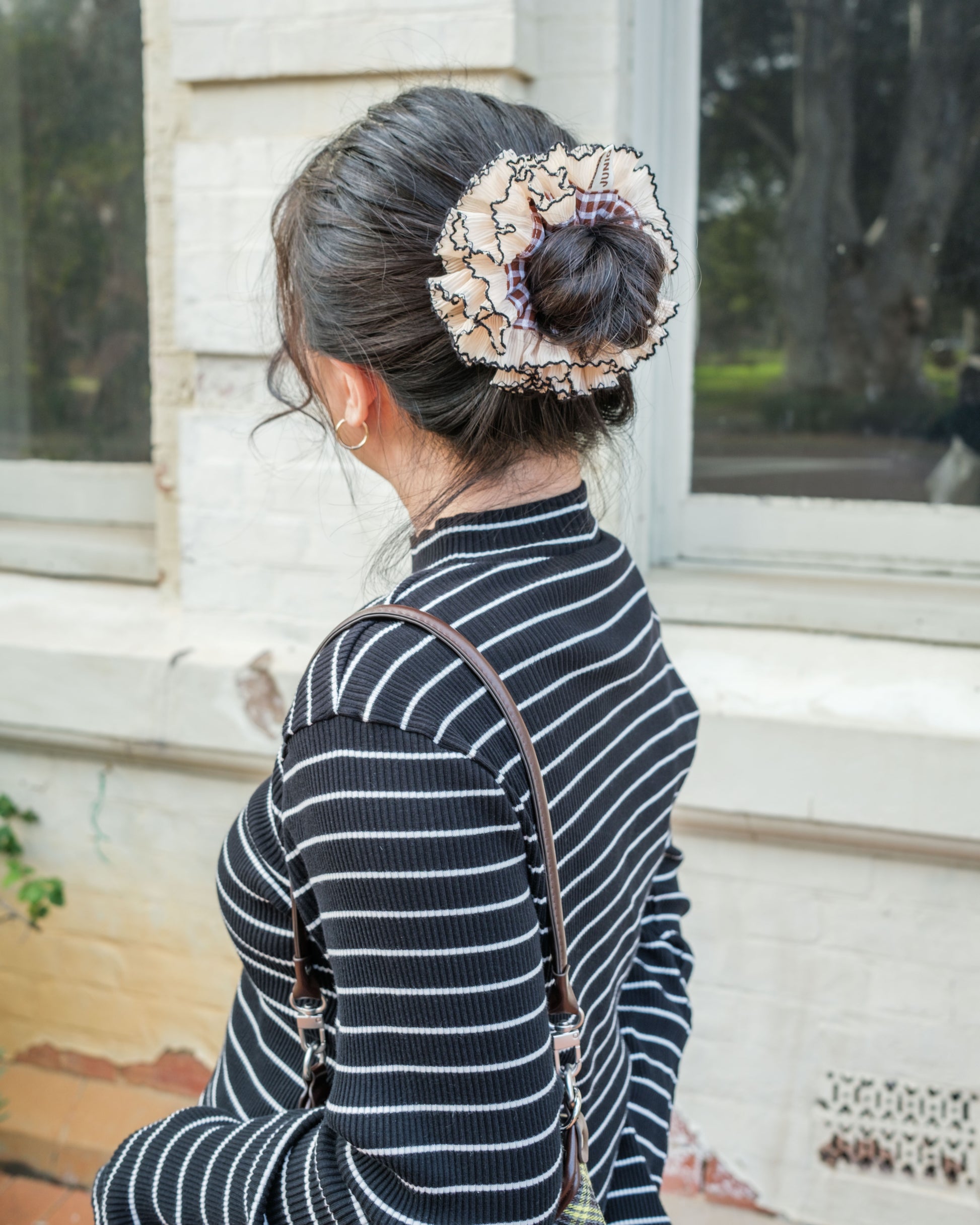 model wearing juniq brand scrunchie, double frilled, brown gingham, beige ruffle trim, in her bun