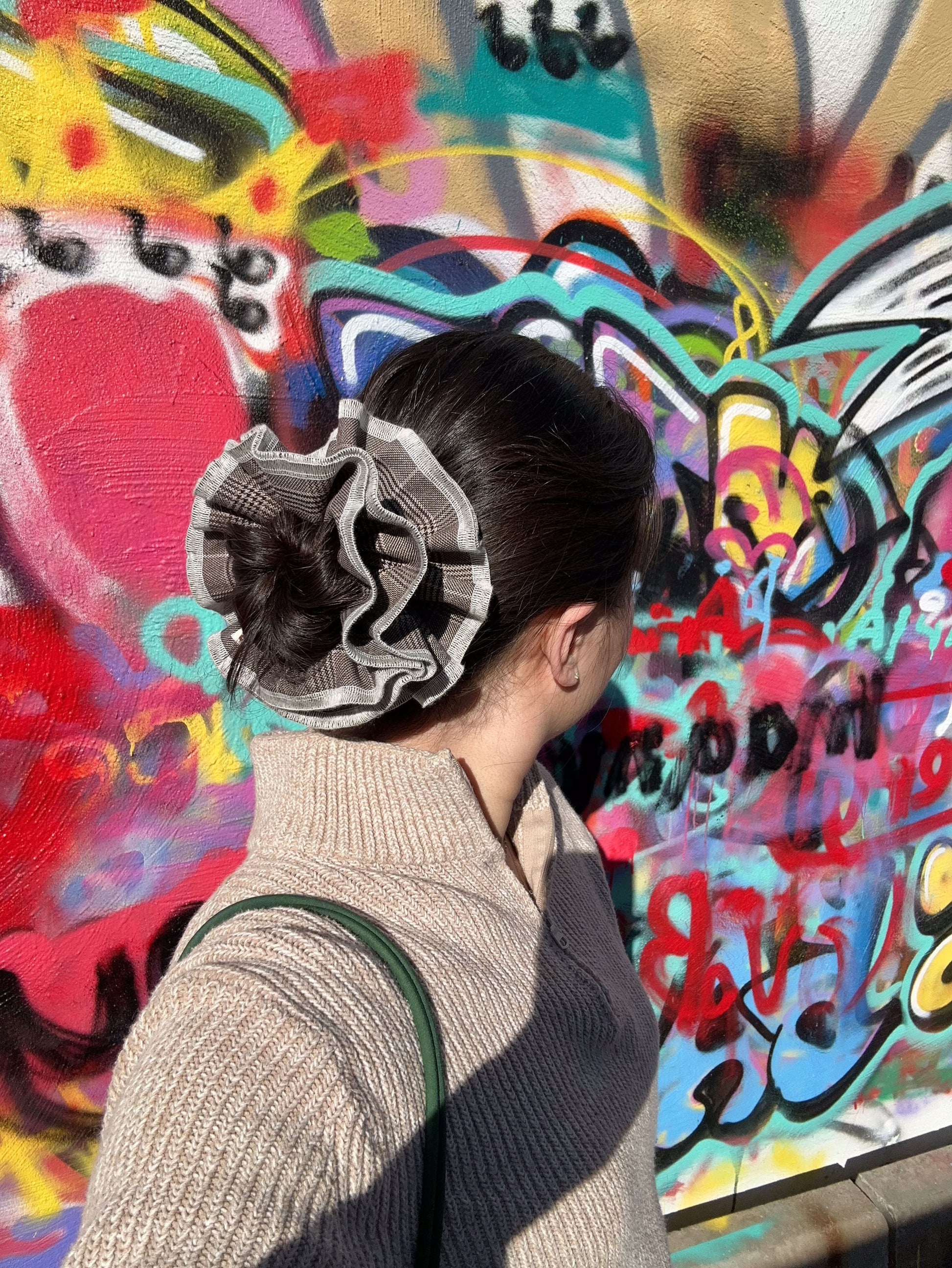model wearing juniq brand scrunchie, glen plaid, brown color, on her bun