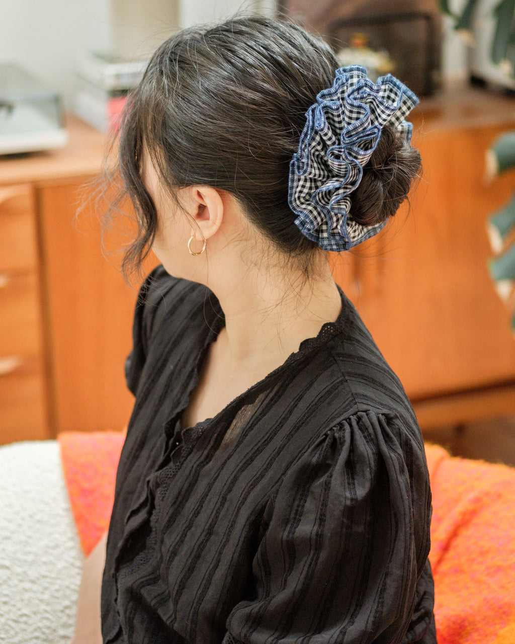 model wearing juniq brand scrunchie, black gingham checkered, blue overlocked trim, quad layers