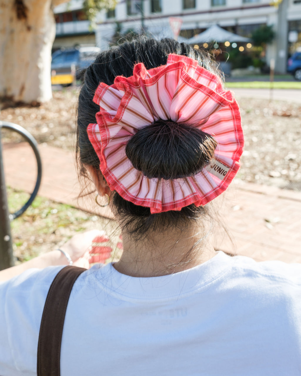 model wearing juniq brand scrunchie, red-pink stripes, overlocked trim, double layers