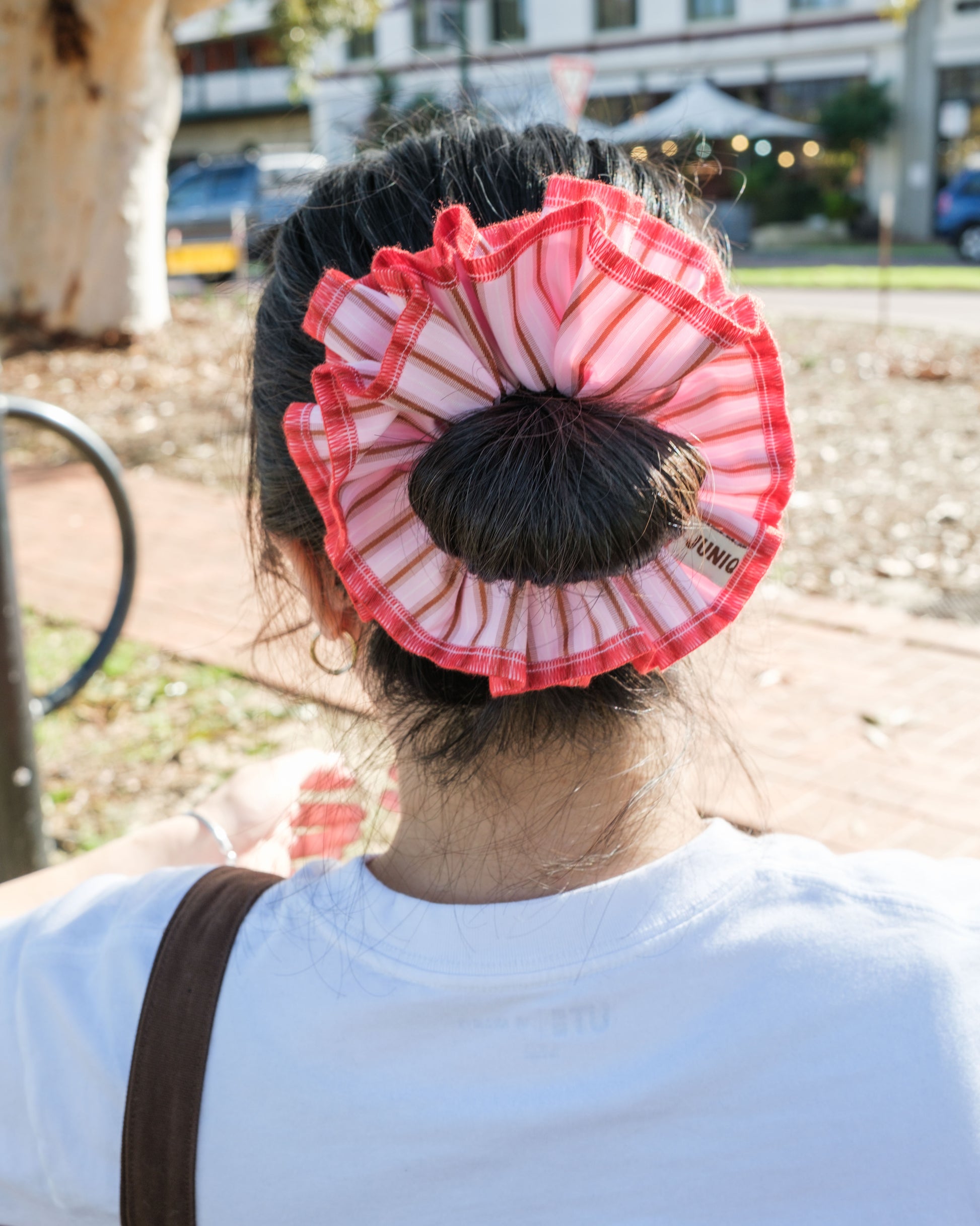 model wearing juniq brand scrunchie, red-pink stripes, overlocked trim, double layers