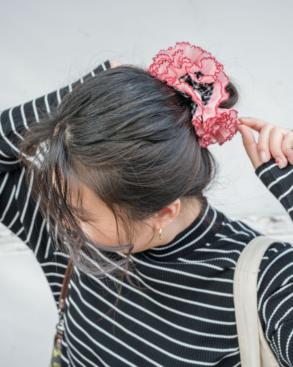 model wearing juniq brand scrunchie, double frilled, ruffled, black gingham with pink trim, in her bun