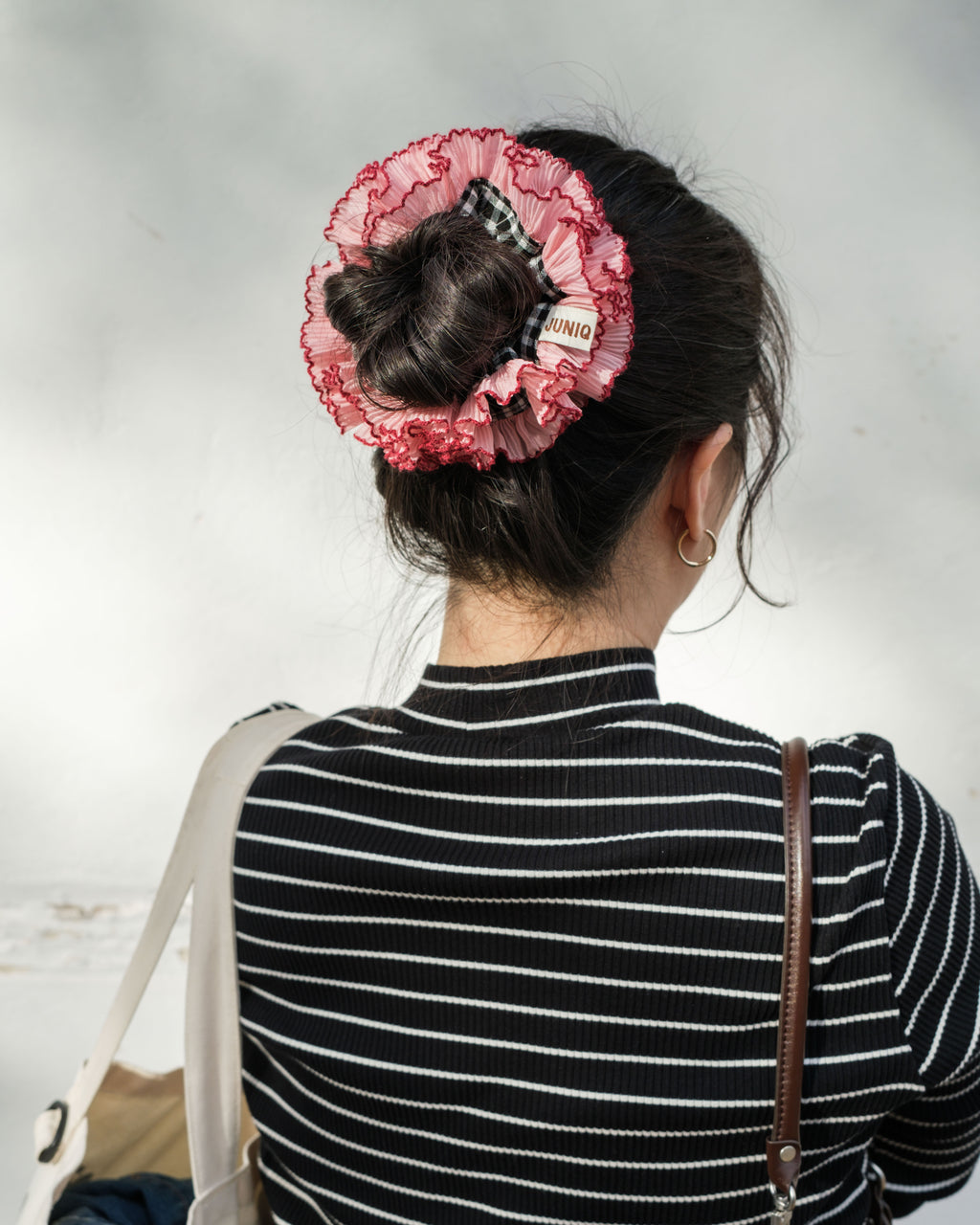 model wearing juniq brand scrunchie, double frilled, black gingham, pink ruffle trim, in her bun 