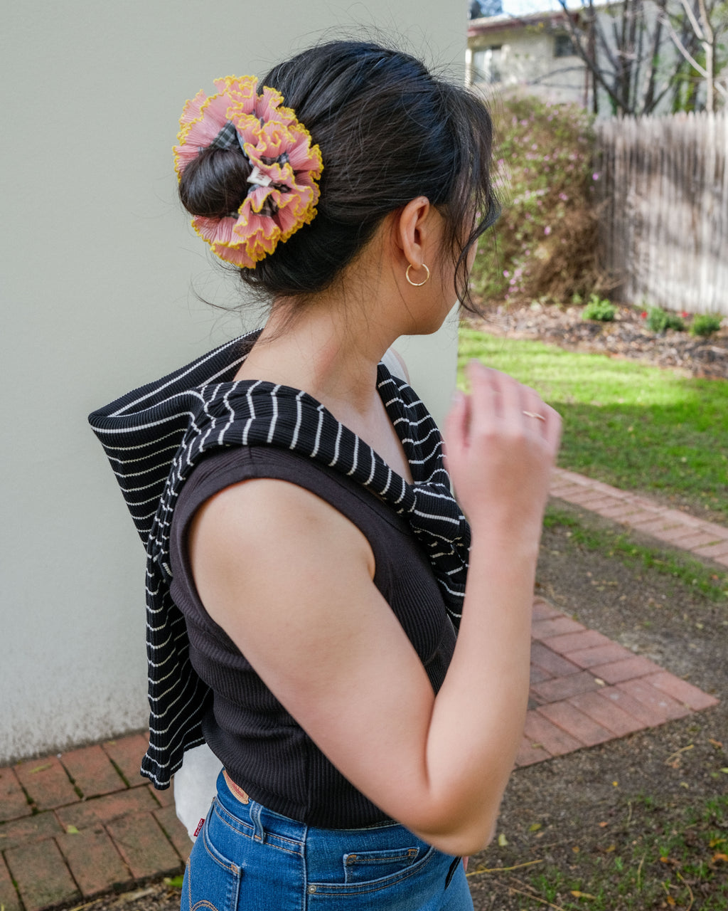 model wearing juniq brand scrunchie, double frilled, sage gingham, pink ruffle trim, in her bun 