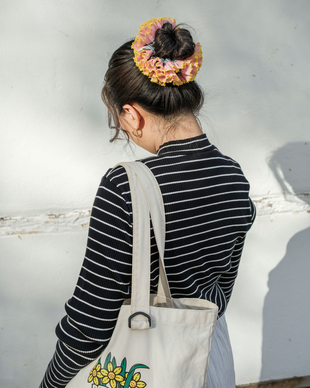 model wearing juniq brand scrunchie, double frilled, sage gingham, pink ruffle trim, in her bun 