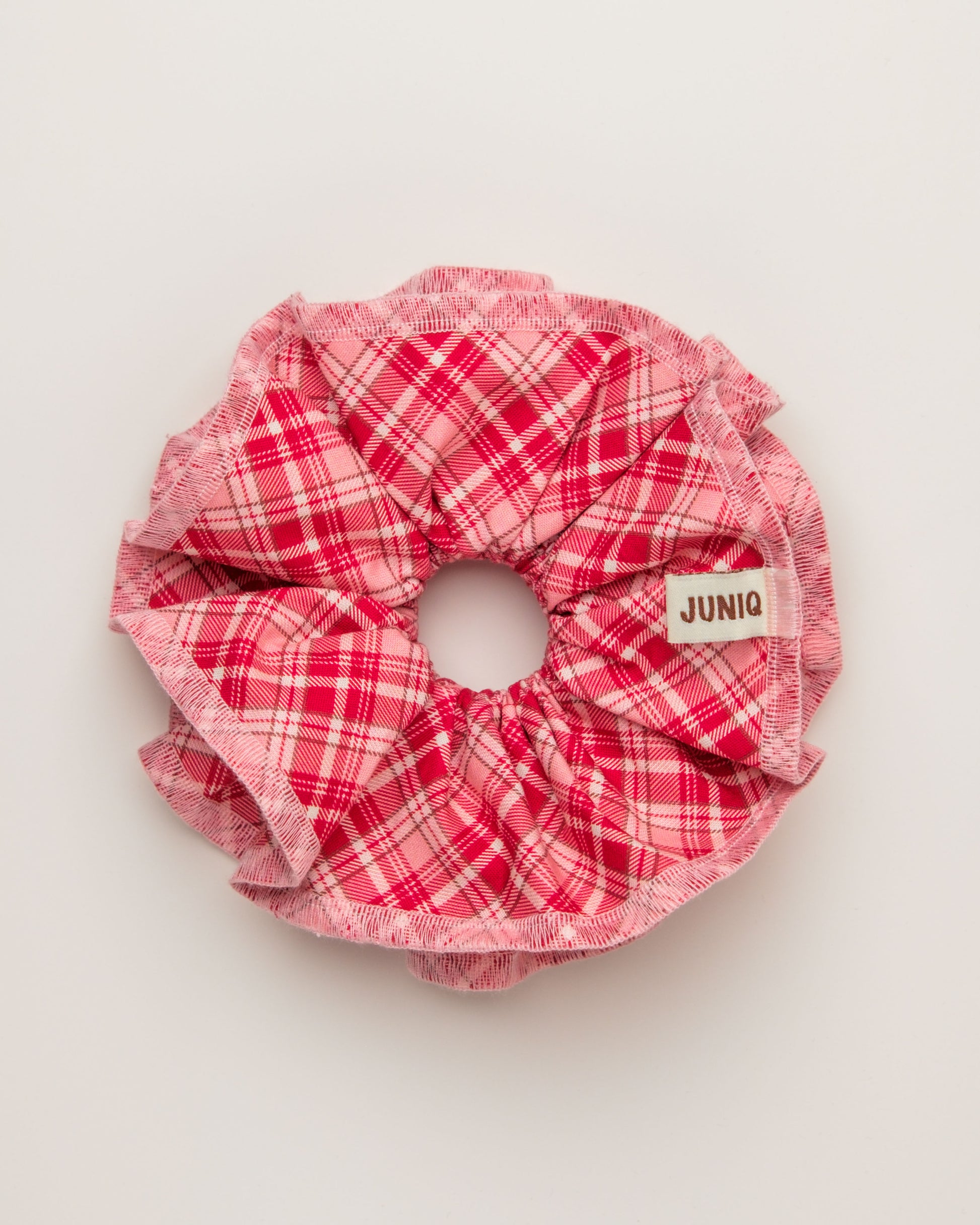 Red plaid scrunchie juniq label on a light grey background